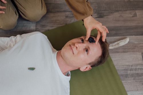 Free A man lying down during a crystal healing ritual indoors on a yoga mat. Stock Photo