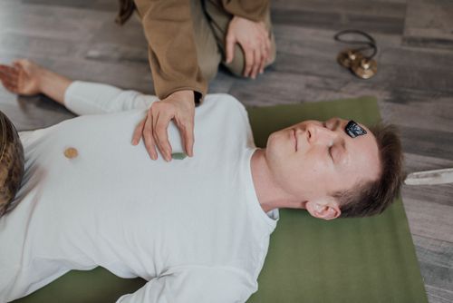 Free A man lies peacefully with crystals during a chakra healing meditation session indoors. Stock Photo
