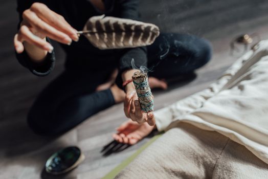 Close-up of a cleansing ritual using sage and a feather, depicting wellness and meditation.