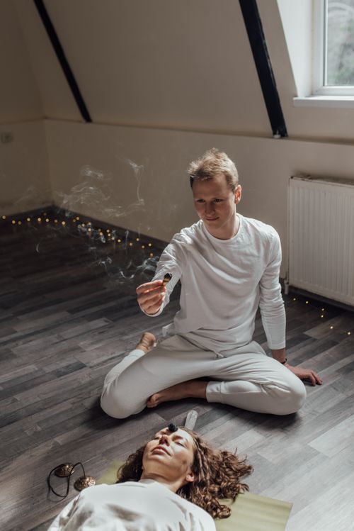 Free A peaceful meditation session indoors with a man using incense and a woman lying relaxed on the floor. Stock Photo