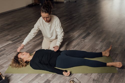Energy practitioner healing relaxed woman on yoga mat