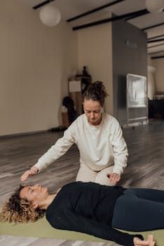 Two women in a serene yoga studio engage in a healing meditation session. Peaceful and focused.