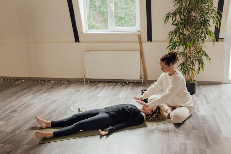 Woman Sitting Beside Woman Lying On The Floor