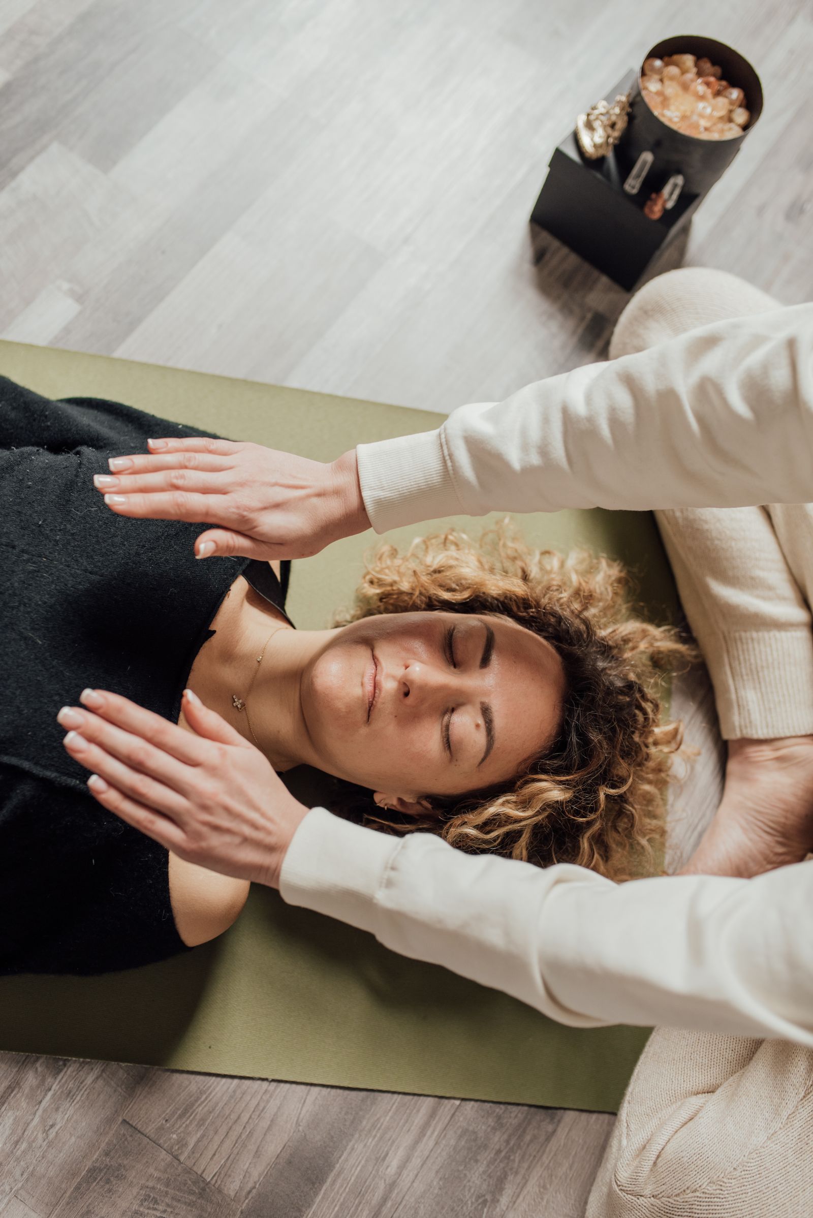 Practitioner holding hands just above a resting client's shoulders during a Reiki session