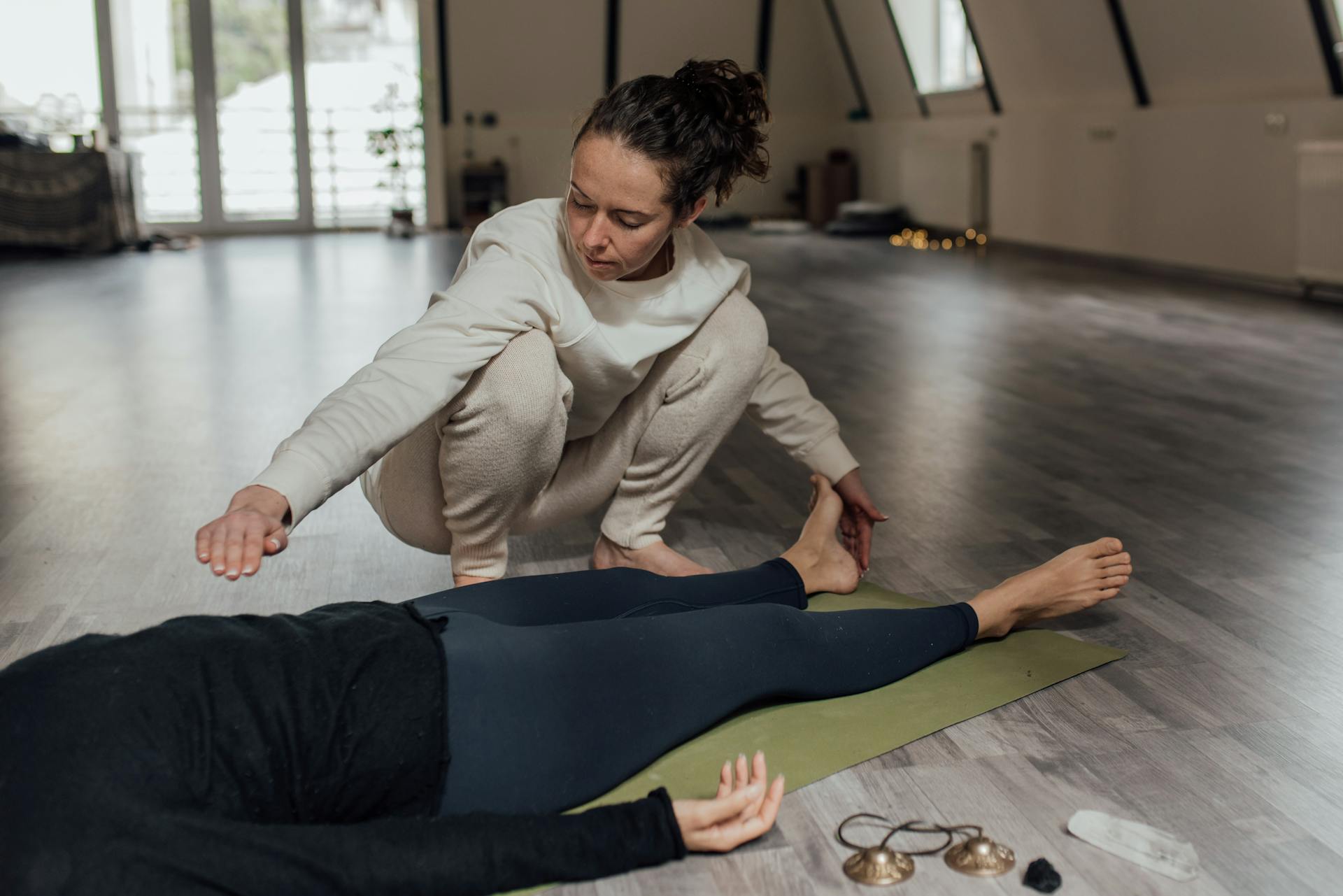 A therapist performs a healing session on a patient lying indoors, emphasizing wellness.