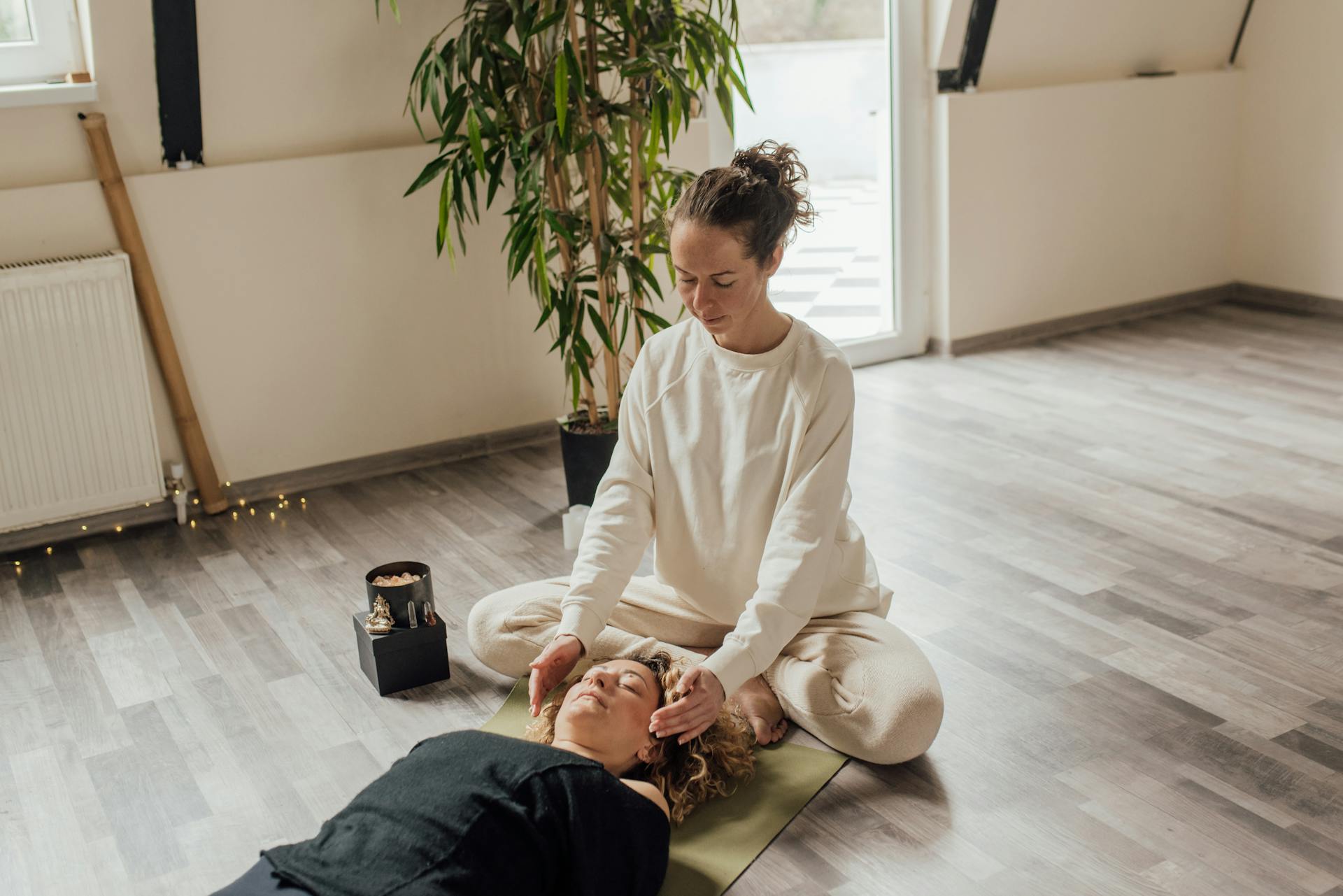 A calming Reiki session indoors with a therapist and patient on a yoga mat, focusing on healing energy.