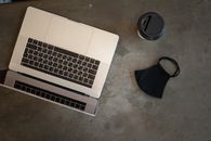 Laptop near face mask on table