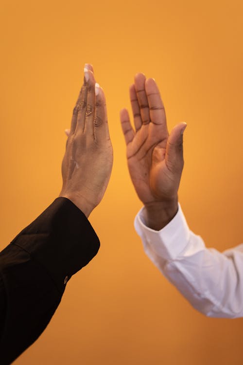 Free African American people in black and white elegant shirts giving high five against yellow background Stock Photo