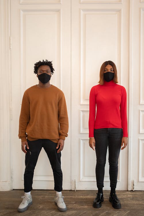 Black woman and man in protective masks standing near door