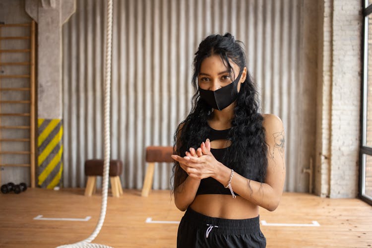 Woman In Mask Rubbing Hands In Gym