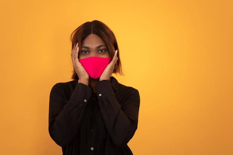 Black Woman With Hands On Head In Pink Protective Mask