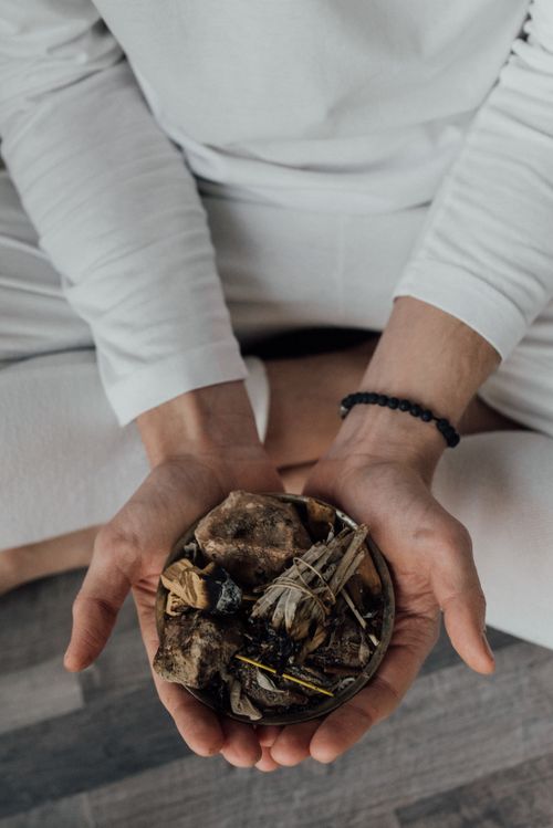Free Person holding a bowl of palo santo and stones, promoting spiritual healing in a meditative pose. Stock Photo