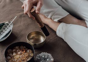 Man meditating with a singing bowl and healing crystals, capturing a serene spiritual practice.