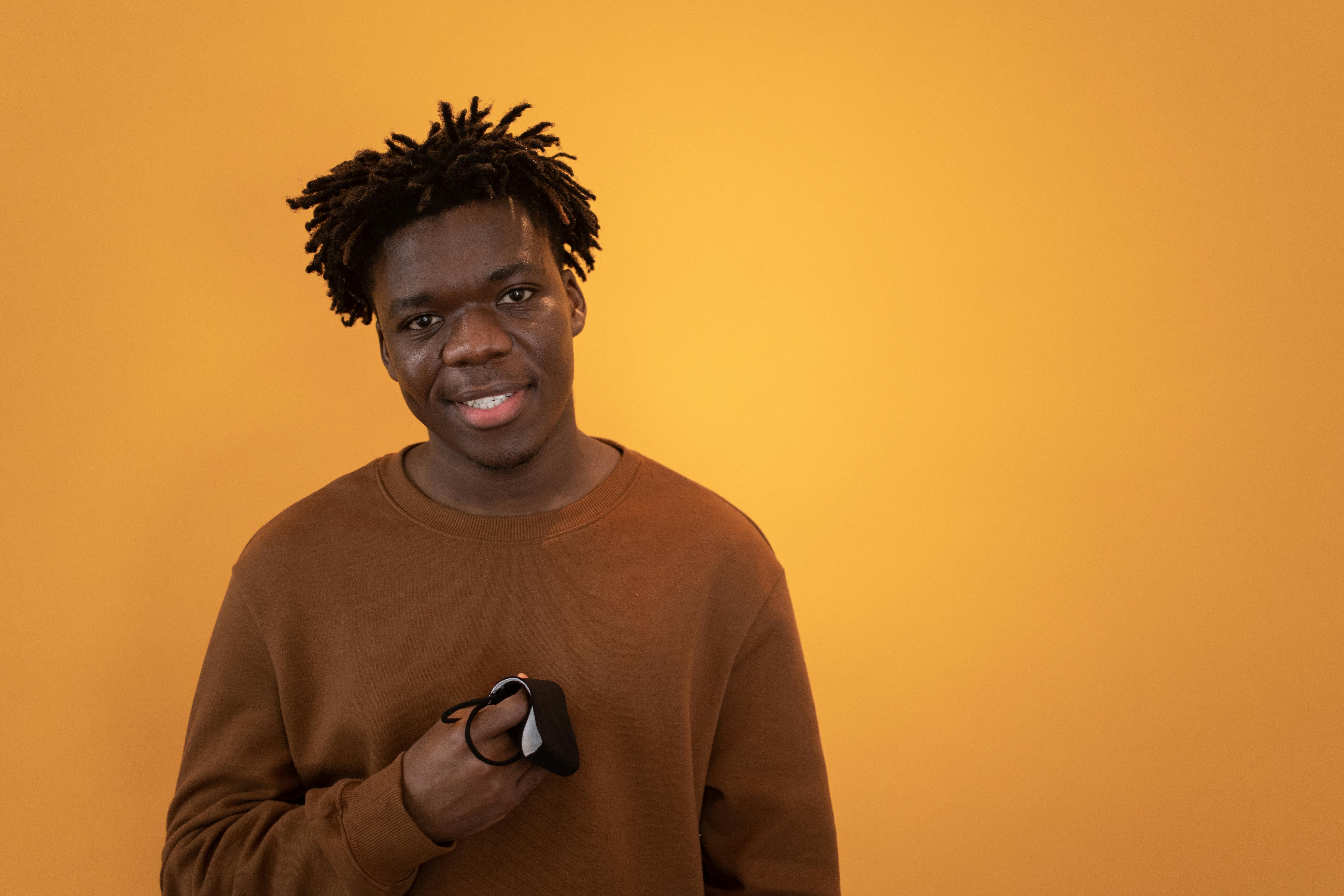 Cheerful black man with arms folded standing against white wall · Free ...