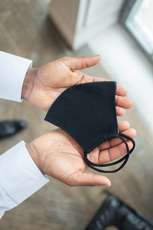 Crop faceless person showing face mask on hands