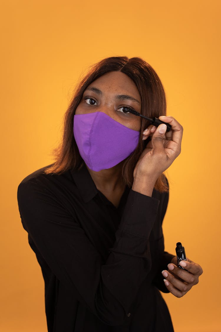 Black Woman In Mask Applying Mascara On Eyelashes