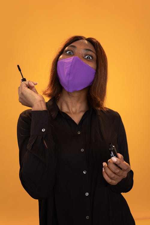 Surprise black woman with mascara standing on brown background