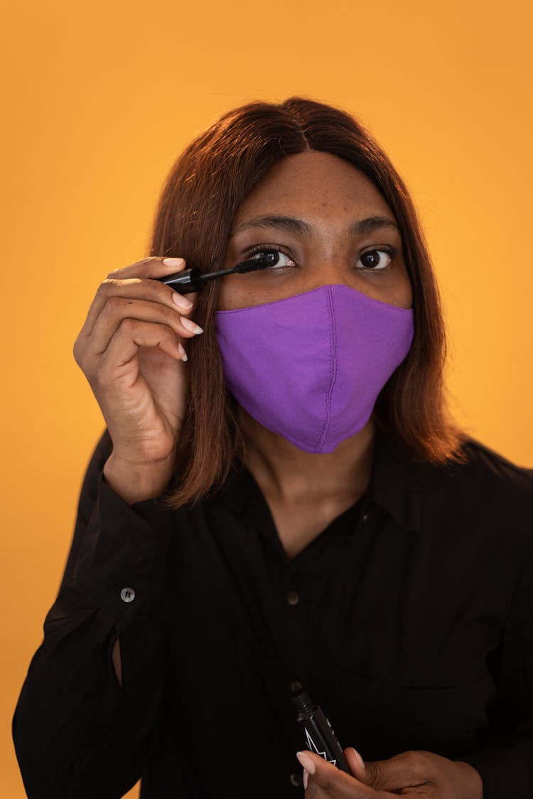 Calm Black Woman In Mask Applying Mascara