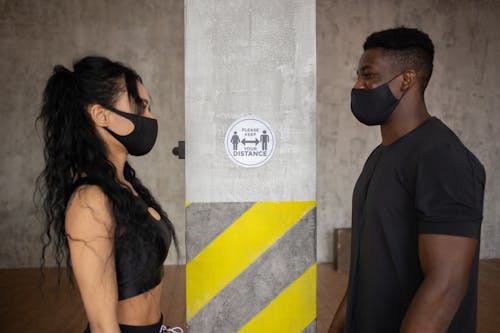 Free Diverse couple standing in protective masks and looking at each other Stock Photo