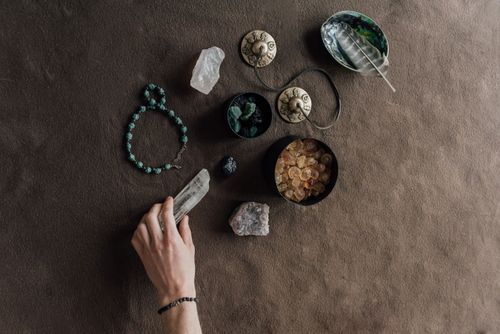 Free Hand arranging spiritual tools and crystals on a natural brown cloth surface. Stock Photo