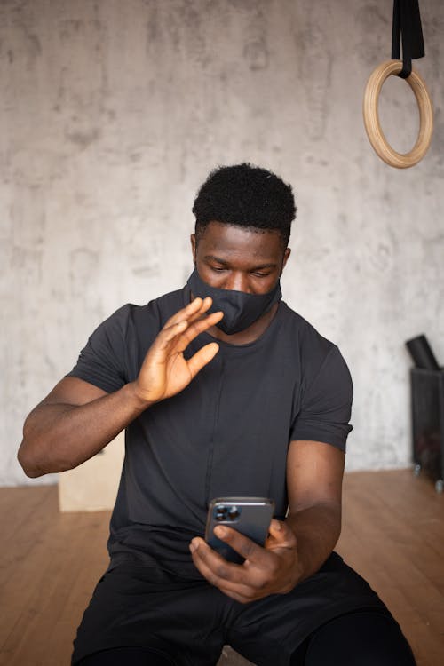 Black sportsman talking on video chat on smartphone in gym