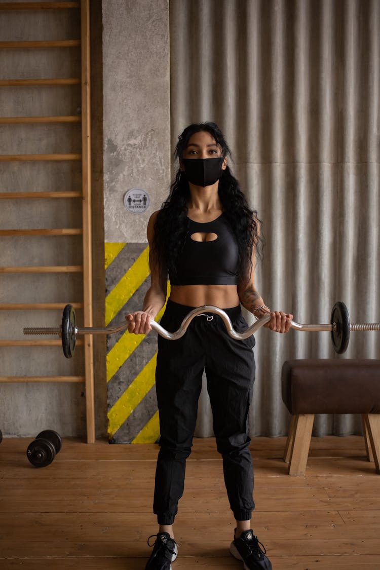 Sportswoman In Mask Training With Weights In Gym