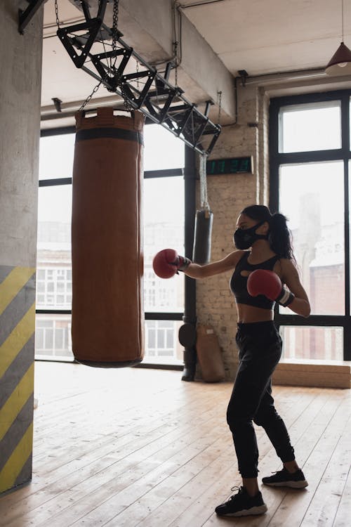 Black boxer punching heavy bag during workout in gym