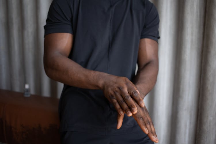 Crop Ethnic Sportsman Applying Antibacterial Gel On Hand Indoors