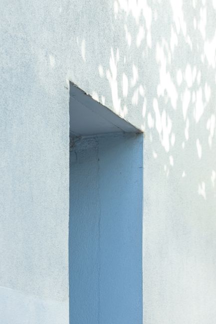 Close-up of a minimalist concrete wall with an indented rectangular opening and shadow play.