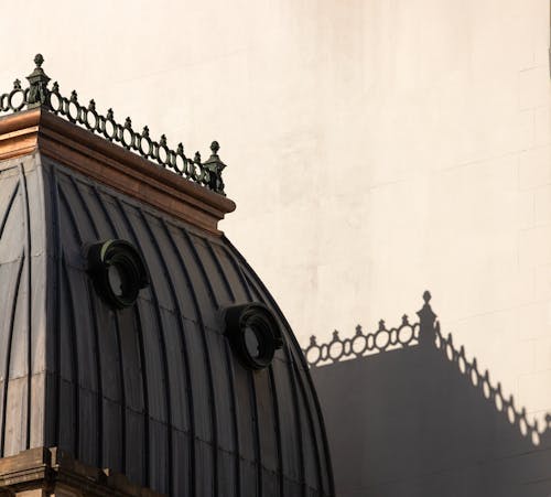 Closeup of a Gray Roof with Round Windows and Shadow on Wall