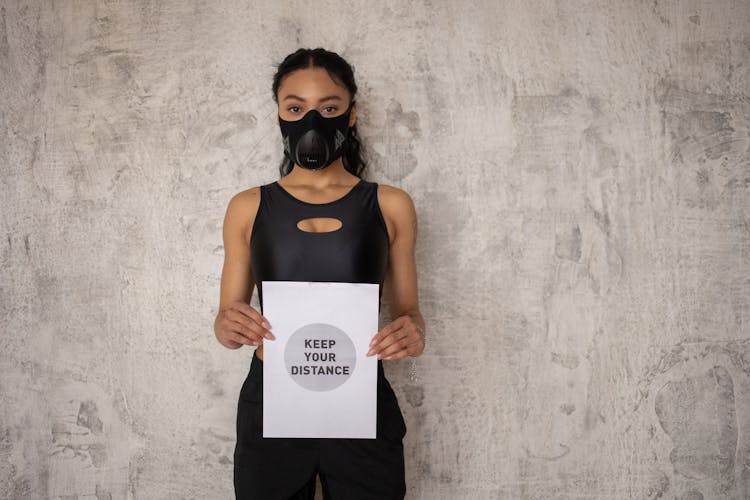 Black Sportswoman In Respiratory Mask Showing Paper With Inscription