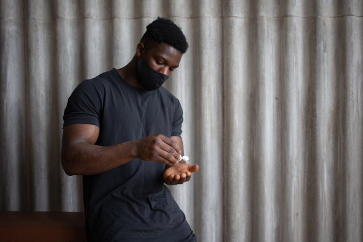 Ethnic Sportsman Applying Antibacterial Gel On Hand During Coronavirus Pandemic