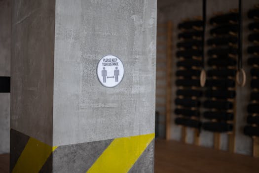 Concrete pillar in a gym with a 'please keep your distance' sign promoting social distancing.