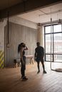 Unrecognizable African American sportswoman touching forehead against male partner in textile mask standing on floor in gymnasium