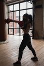 Active black boxer punching heavy bag during workout in gymnasium