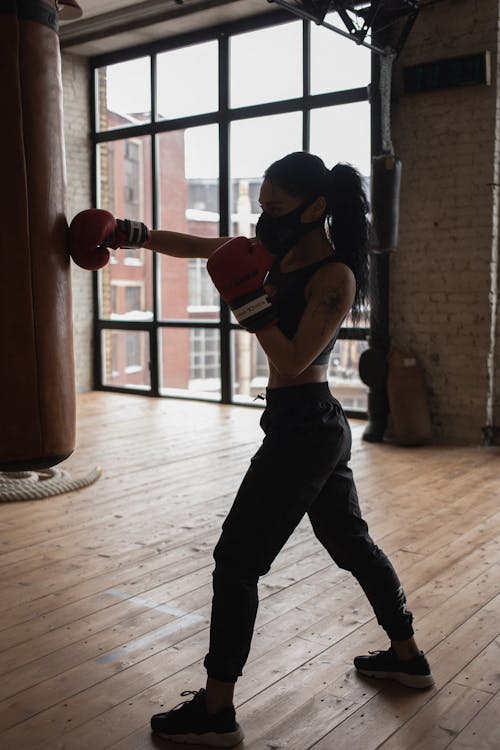 Free Active black boxer punching heavy bag during workout in gymnasium Stock Photo