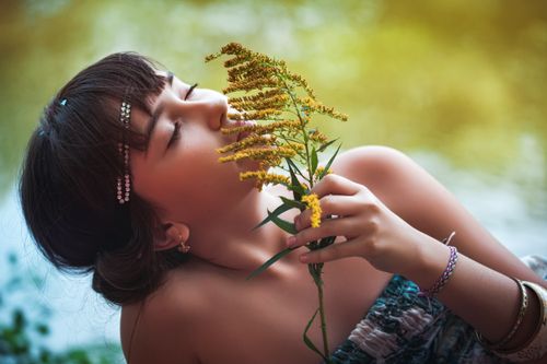 Free Young woman with closed eyes enjoying the scent of yellow flowers in a natural setting. Stock Photo