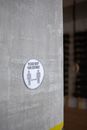 Round sign with Please Keep Your Distance inscription over figures and arrows on cement wall during COVID19 pandemic in gym