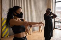 Black sportspeople in fabric masks warming up in gym
