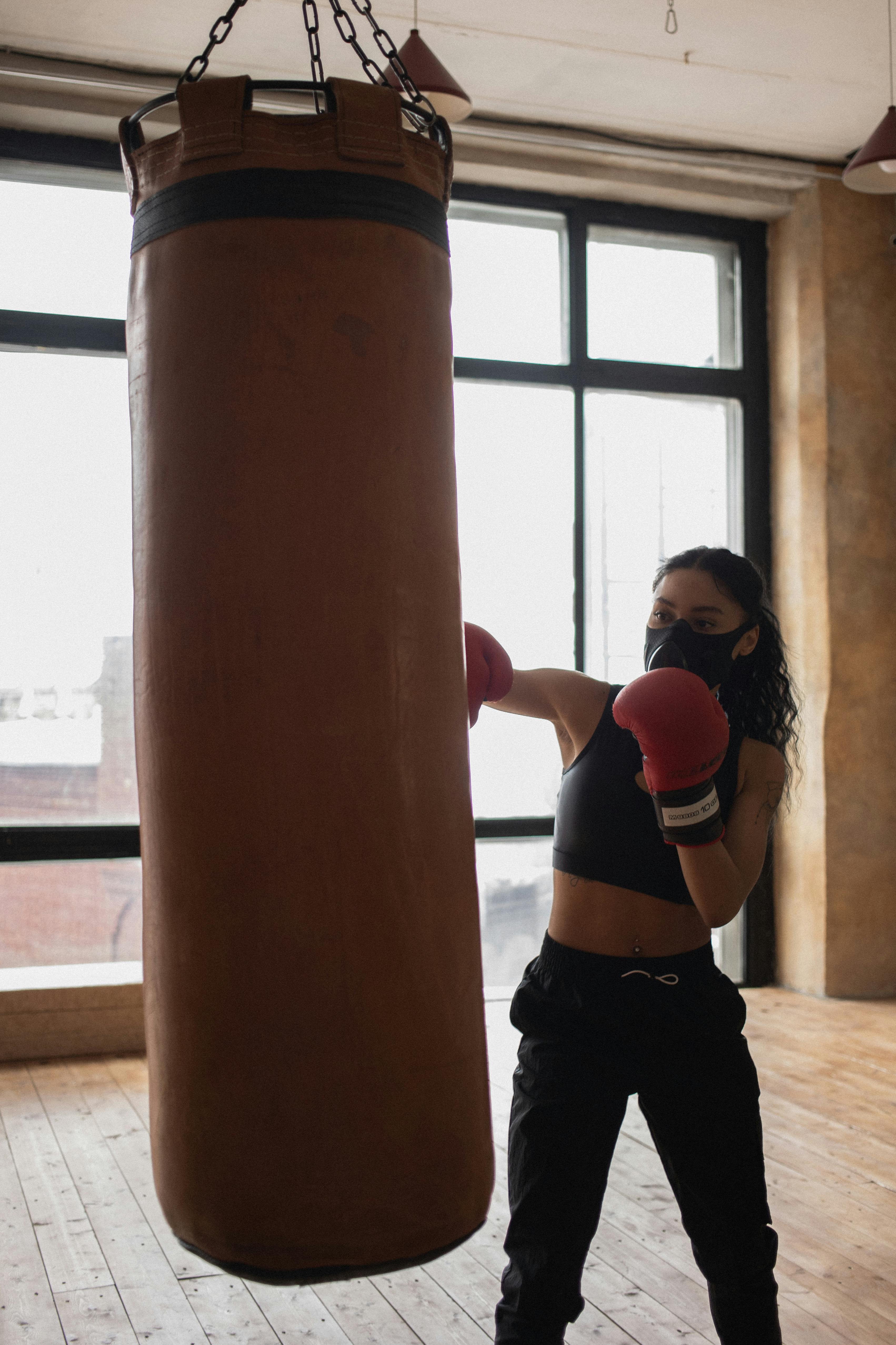 black fighter punching boxing bag during training in gym