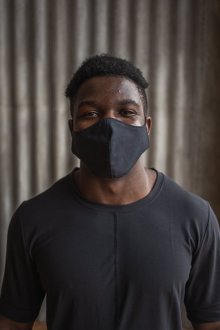 Friendly Black Sportsman In Textile Mask Against Ribbed Wall