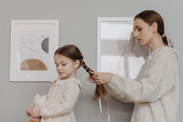 Femme qui arrange les cheveux d'un enfant dans une pièce chaleureuse