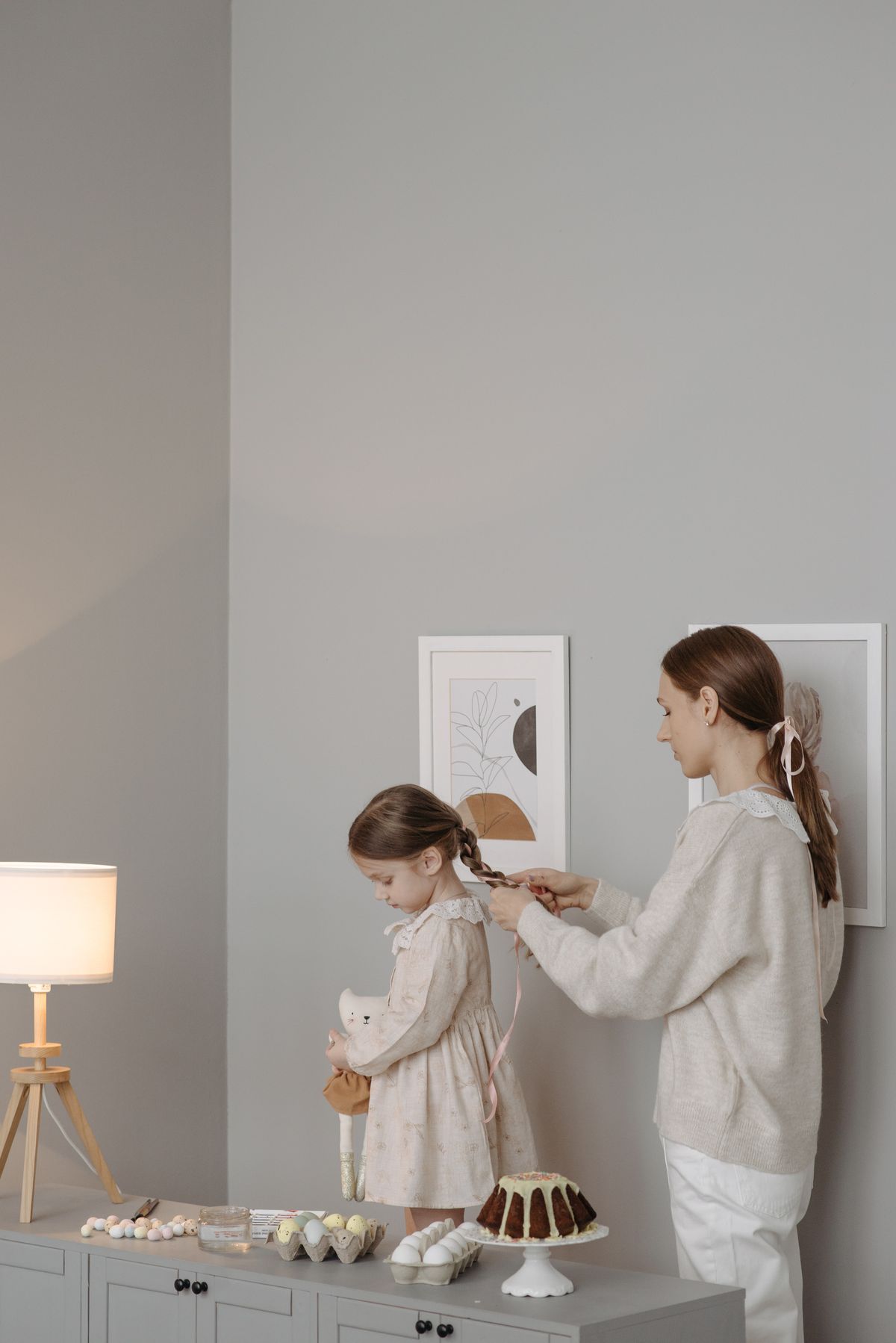 Mother braiding her daughter's long hair at home while creating an everyday family hairstyle