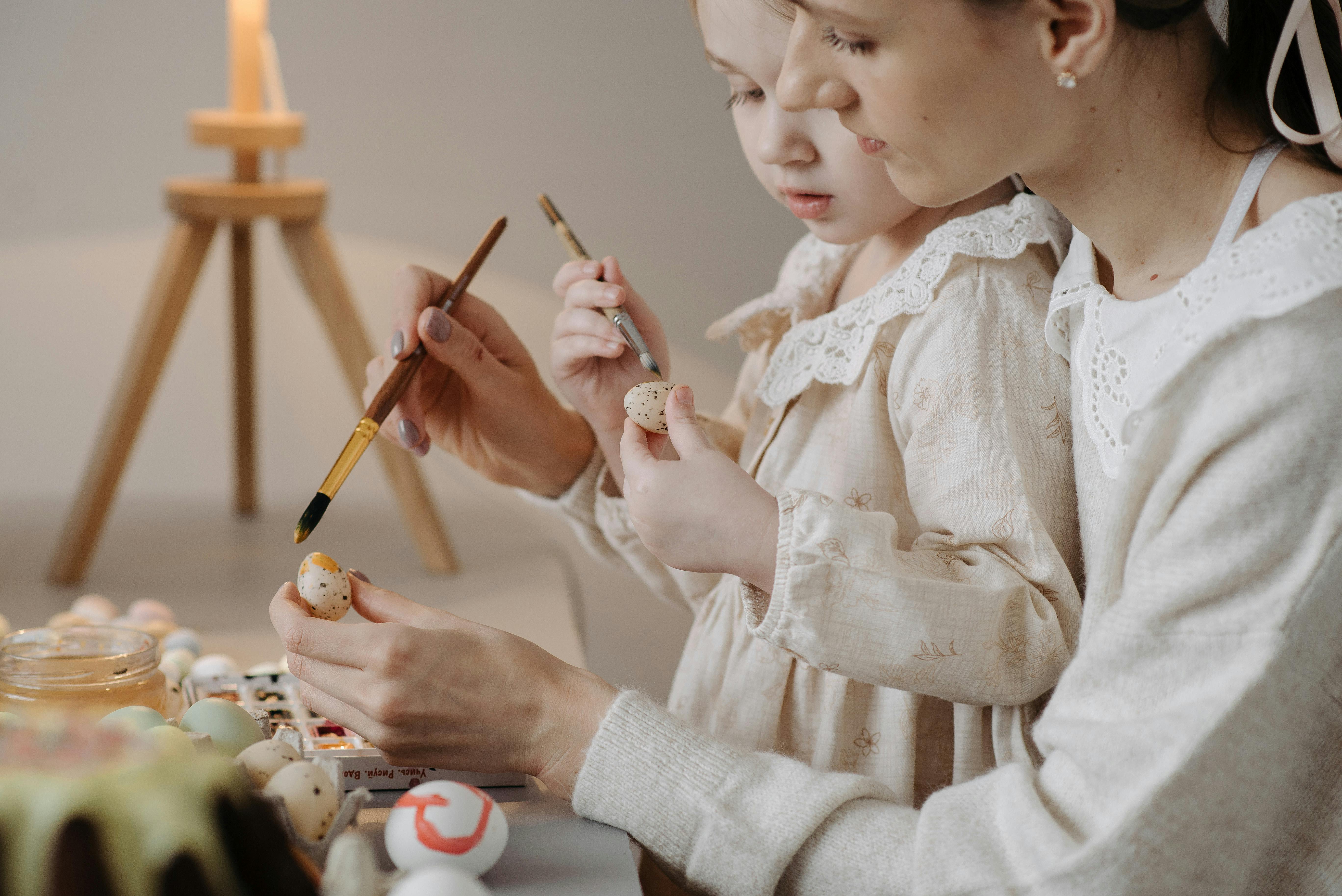 girl and a woman painting quail eggs