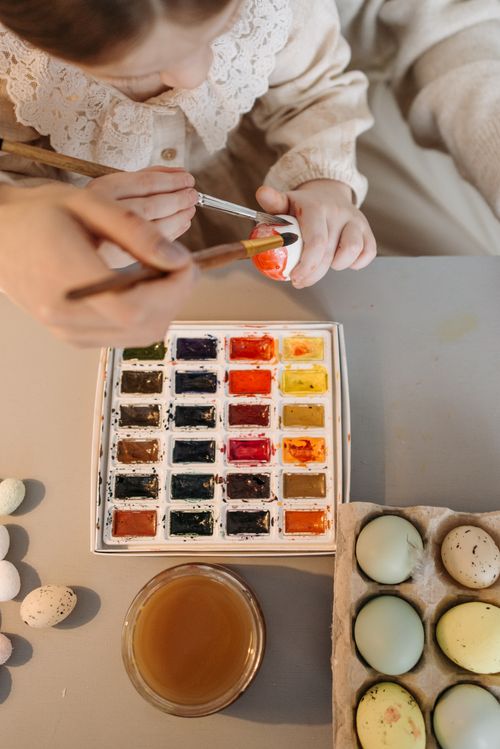 Free Child painting colorful Easter eggs with watercolors. Perfect for holiday creativity and tradition. Stock Photo