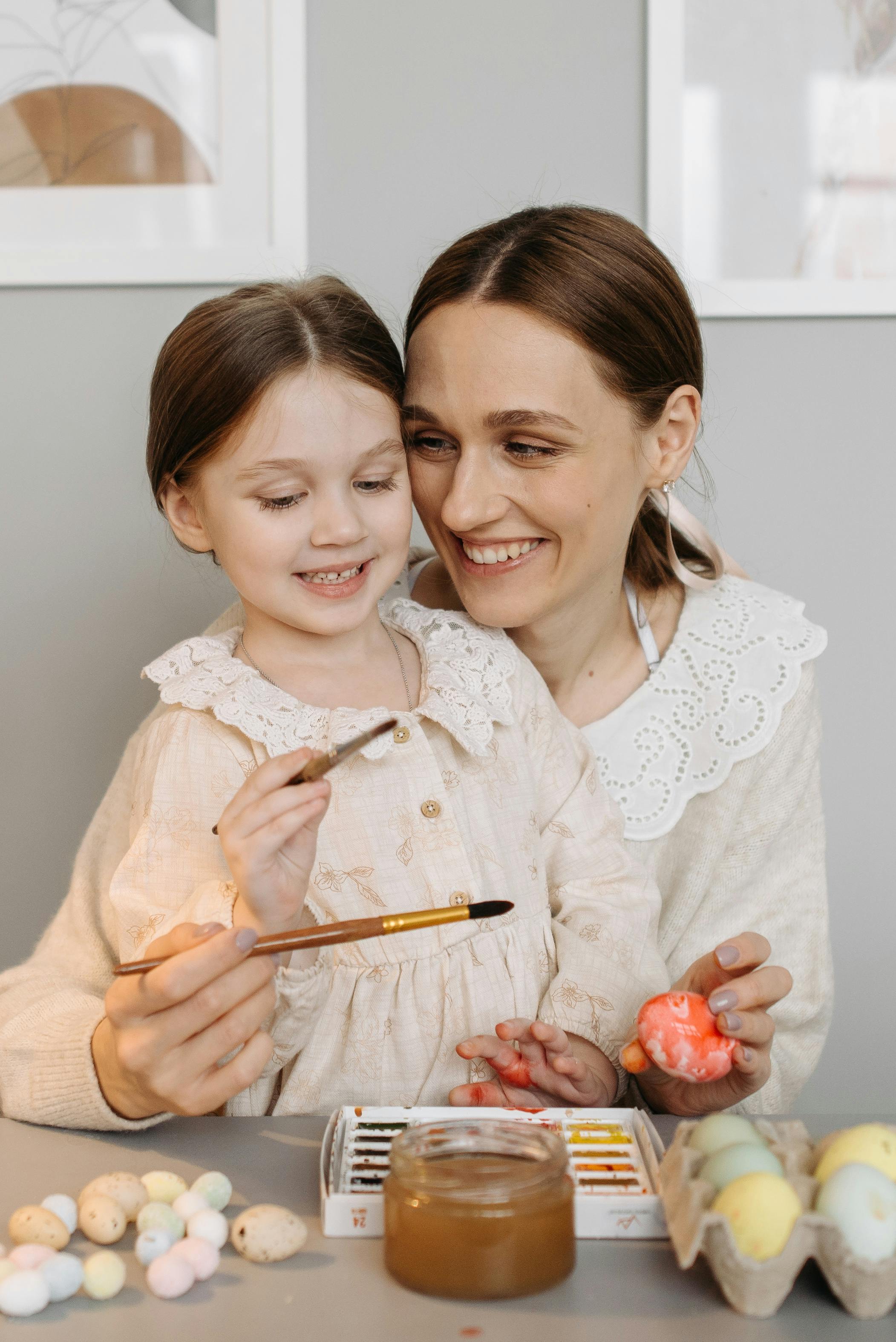 a mother and her child painting eggs