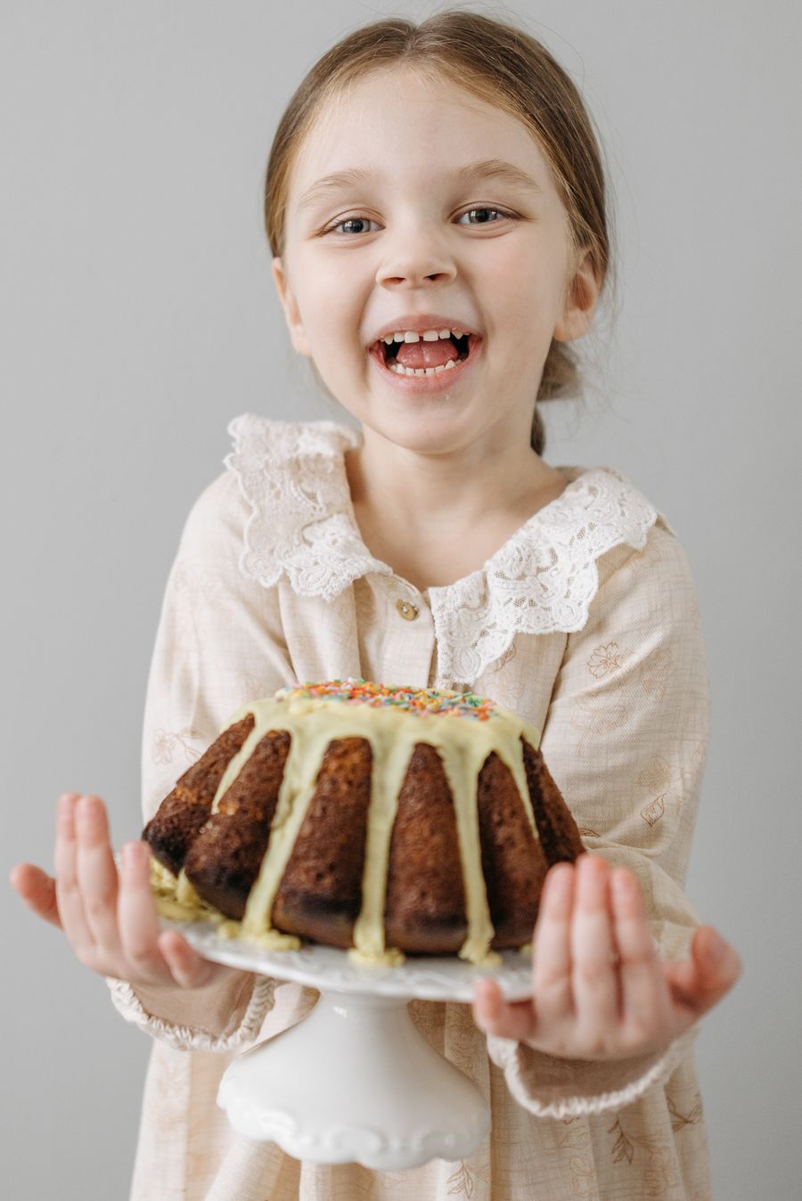 Little baker proudly holding a cake she decorated with icing and sprinkles
