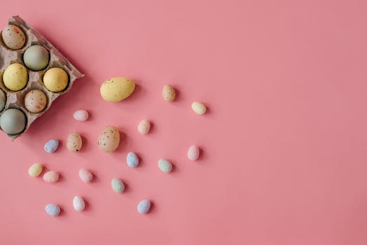 A flat lay of vibrant Easter eggs scattered on a pink surface.