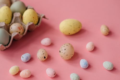 Free Festive Easter eggs scattered on a pastel pink surface, ideal for holiday themes. Stock Photo