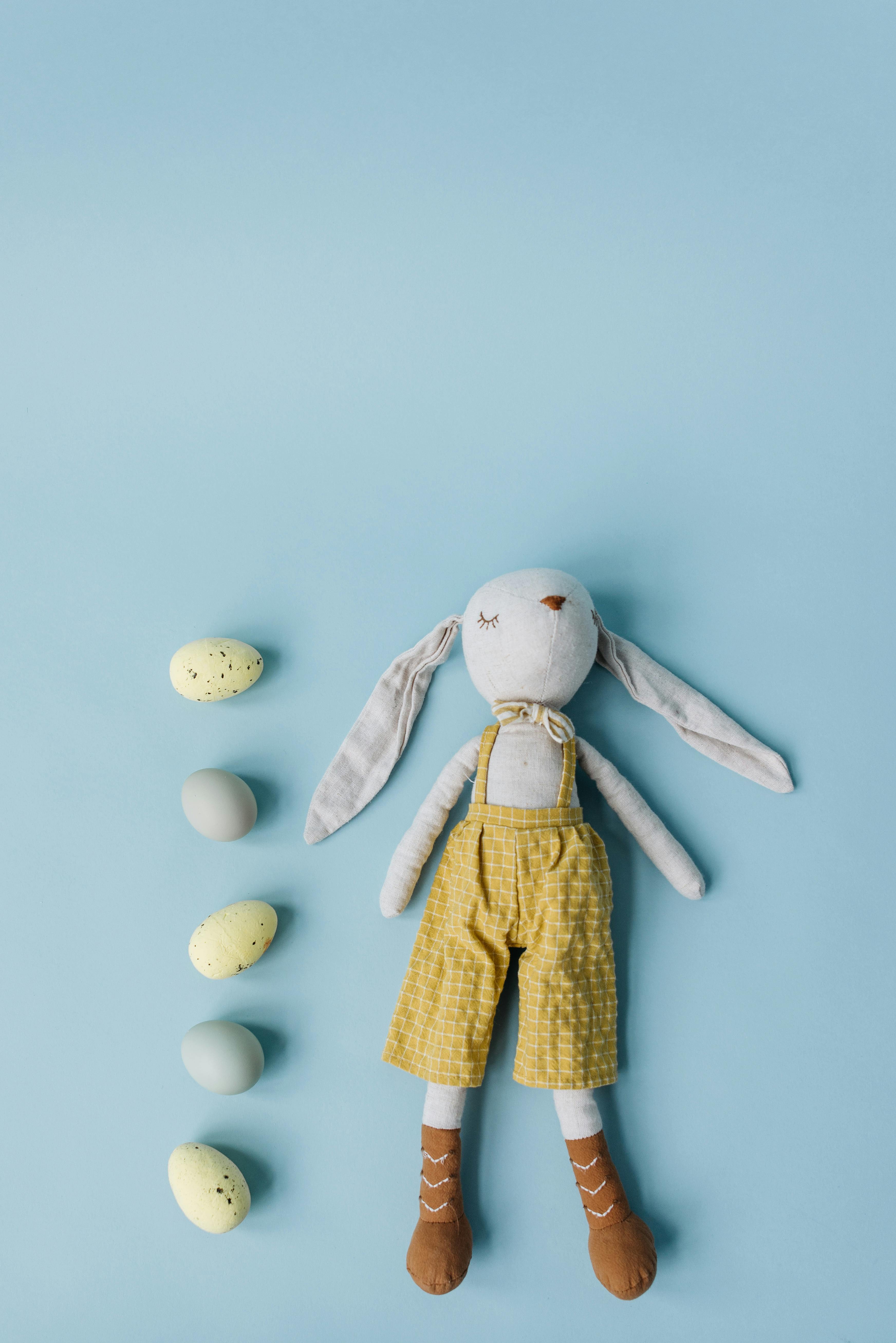 white and yellow rabbit plush toy on blue background